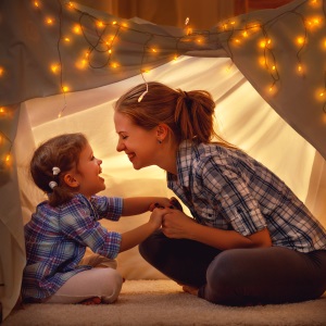 woman and girl playing in tent with fairy lights