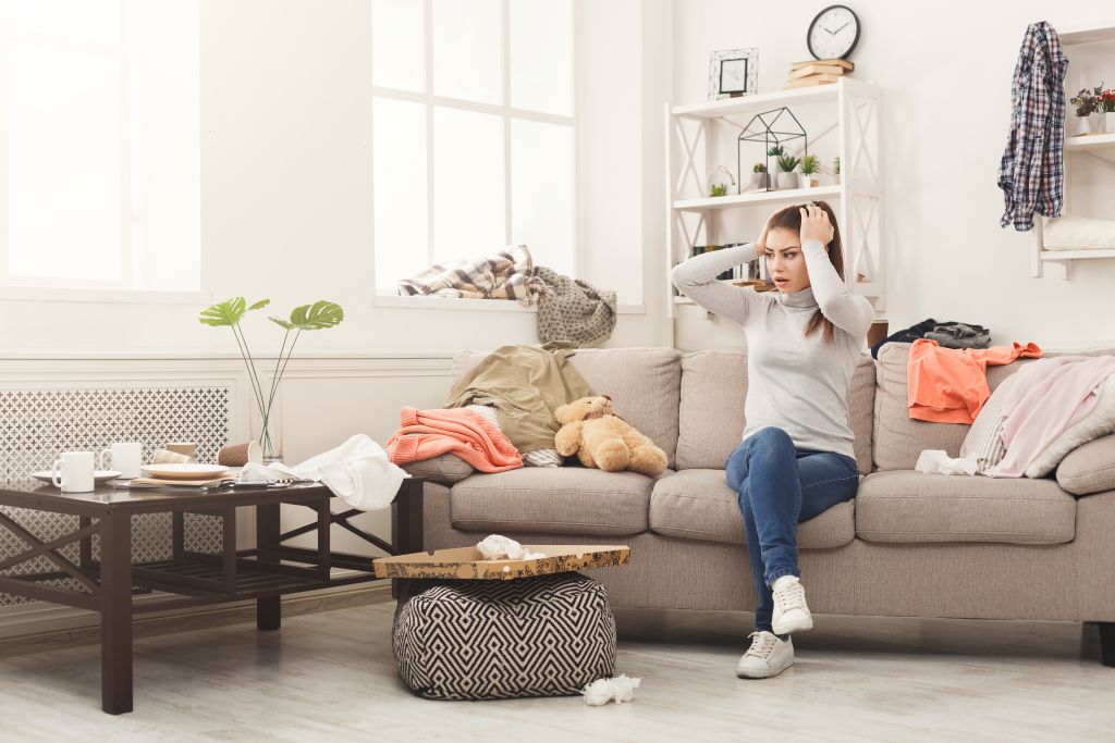 Woman with hands on head surrounded by mess