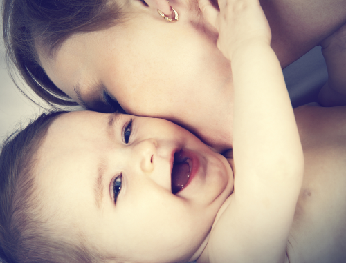 Woman kissing laughing baby