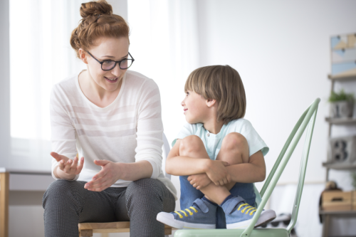 Woman talking to boy sitting on chair