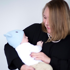 Louise holding a gorgeous baby in a blue bonnet